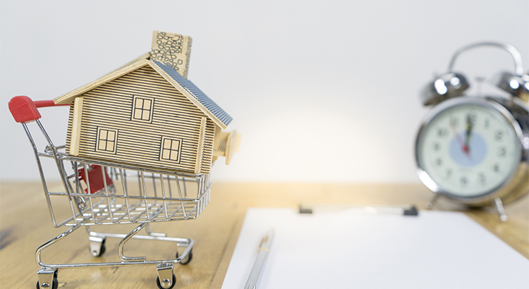 Alarm clock, house model and shopping cart model, home buying moment concept
