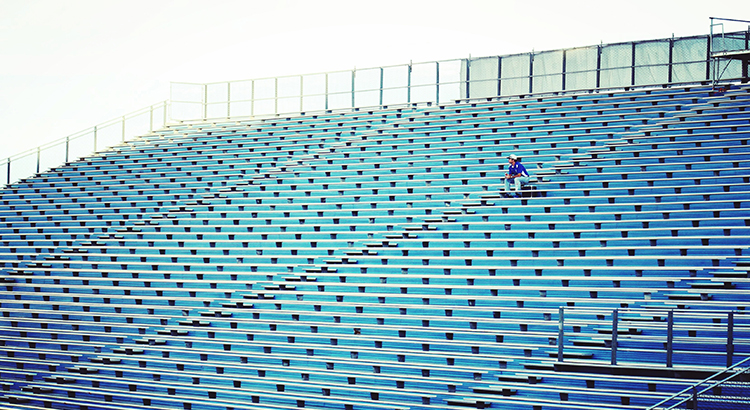 Man Sitting On Bleachers At Stadium